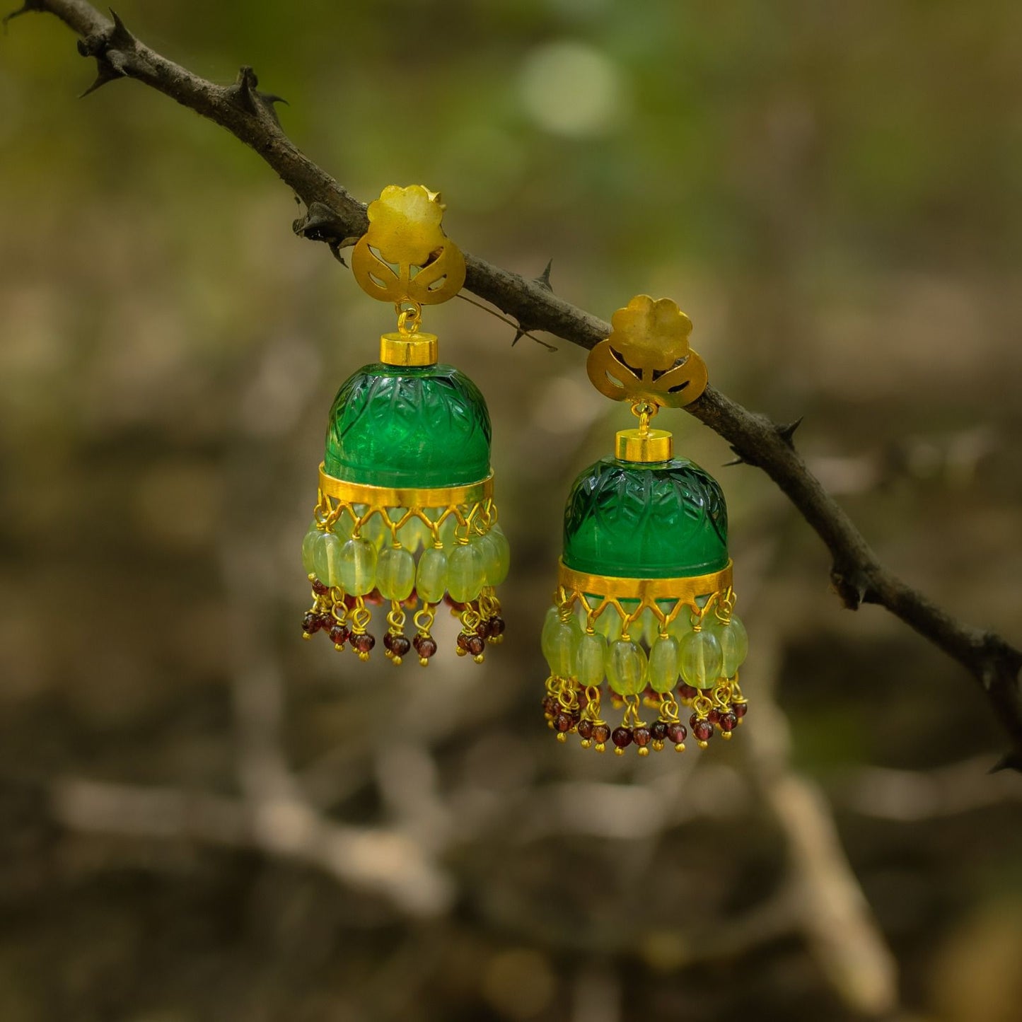 Green crystal stone jhumka with carving, flower top with post. Sterling silver with 24 karat gold plating.